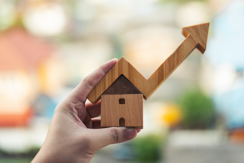 hand holding wooden house model, market growth, interest rates, real estate